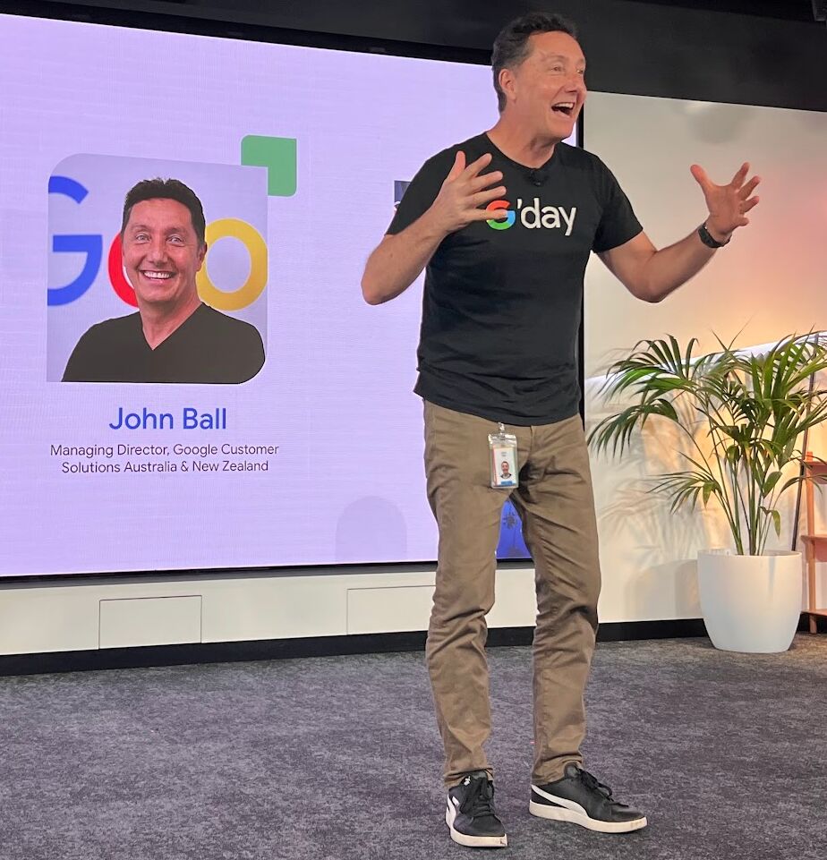 a man in front of a screen on stage giving a presentation