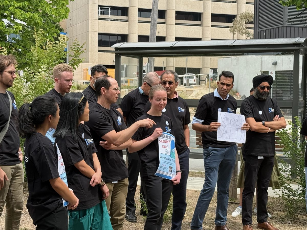 Doctors in black shirts speaking with each other at a protest rally