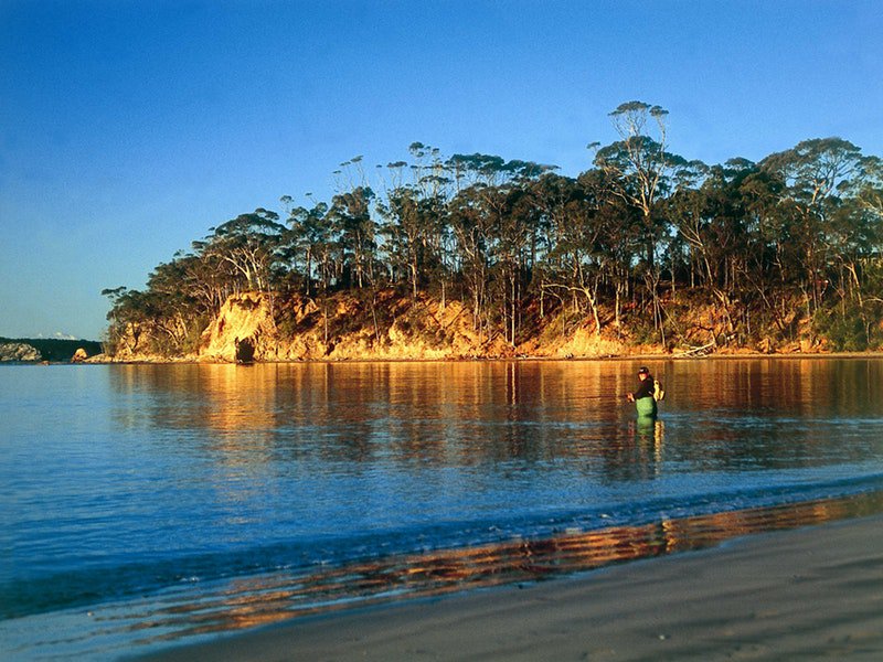 Man wading in water fishing at Batemans Marine Park.