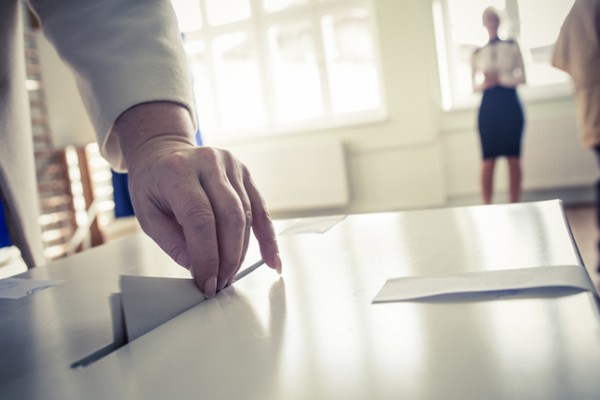 Person submitting vote into ballot box.