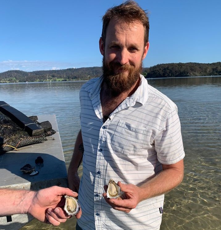 Chef Paul West holding an oyster at a South Coast estuary farm.