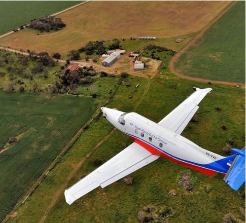 Aerial image of Royal Flying Doctor Service plane flying over rural land.