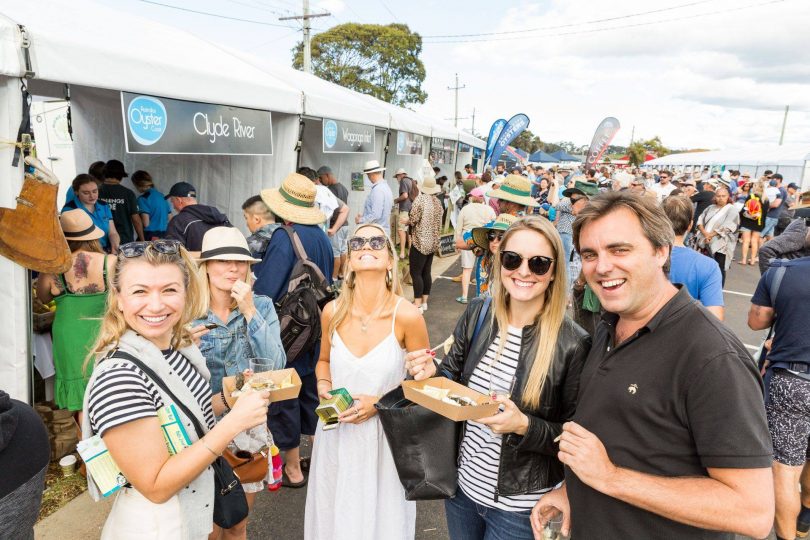 Group of people smiling and holding oysters at the 2019 Narooma Oyster Festival.