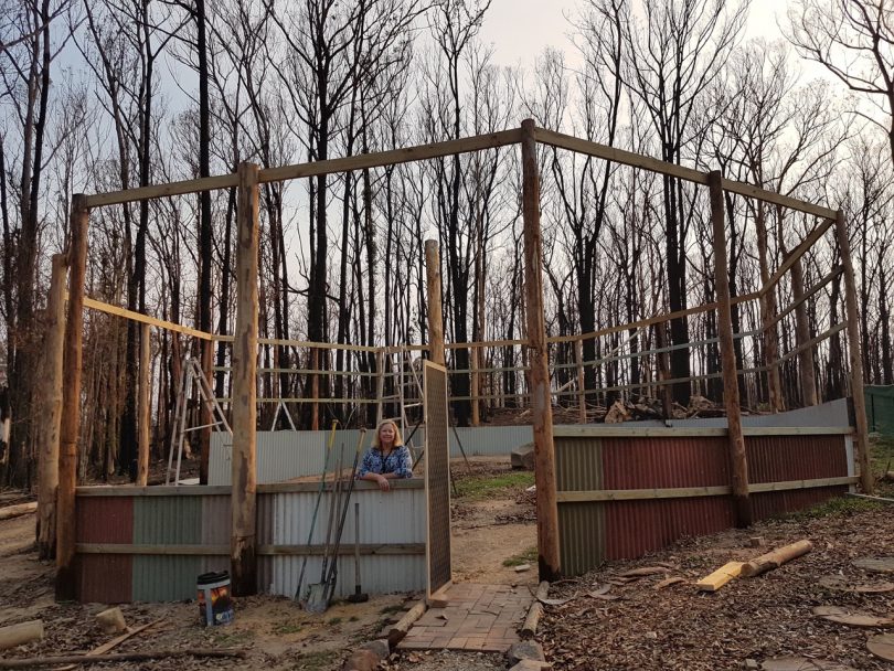 Lorita Baumann standing in the newly built raptor enclosure on her burnt property.