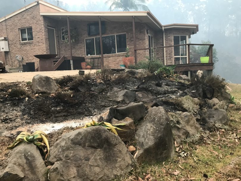 House still standing surrounded by burnt bushland.