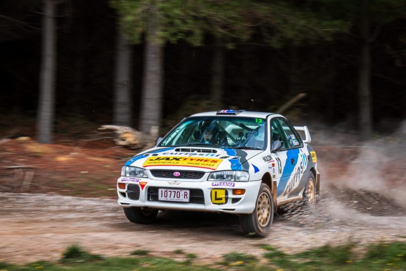 Taylor Gill driving rally car on dirt road.