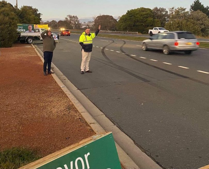 Trevor Hicks standing roadside waving to motorists.