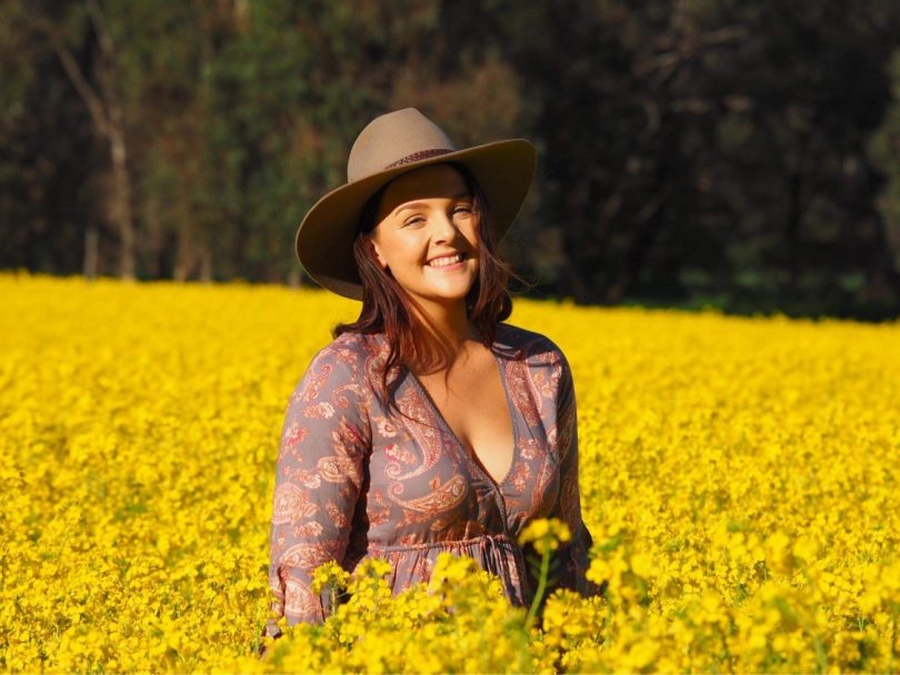 Georgia Corbett standing in field of canola.