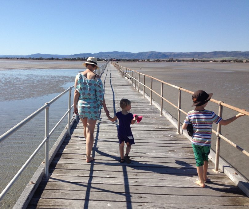 Mother walking with two kids on pier.
