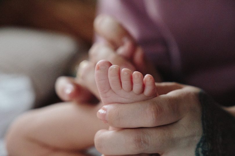 Adult holding baby's foot.