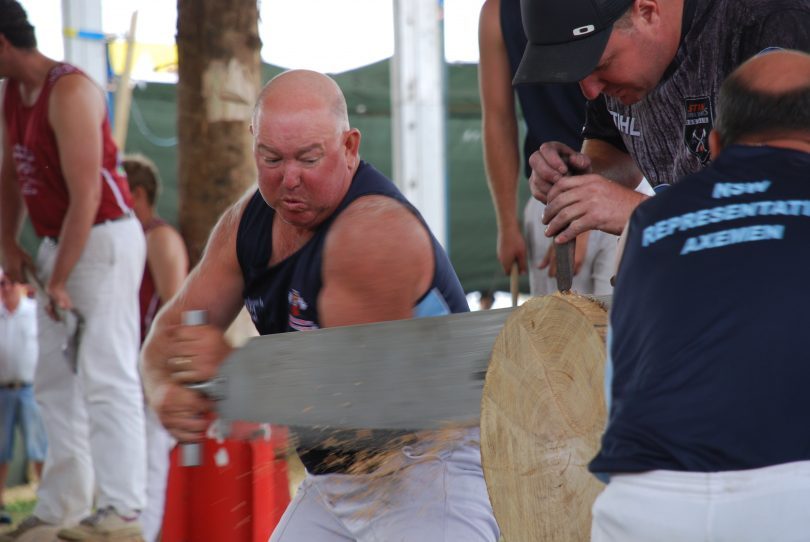 Man sawing log in competition at country show.