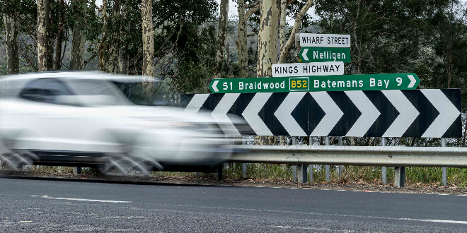 Car passing road signs on Kings Highway.