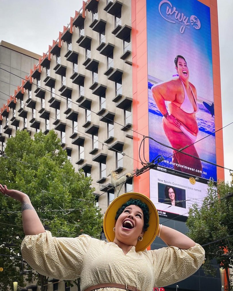 April Hélène-Horton stands under her billboard