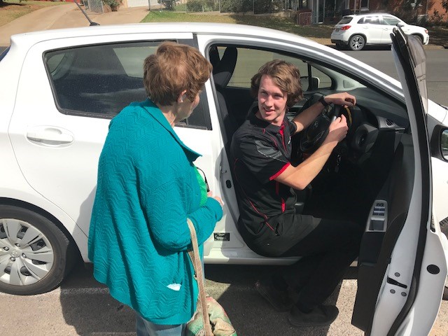 Jamie Luff sitting in vehicle with elderly woman looking on