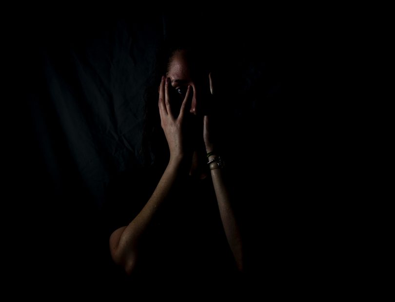 A scared woman covering her face with her hands