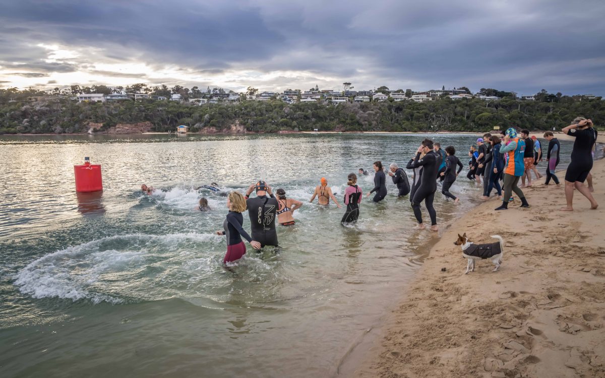 People in wetsuits walking into water