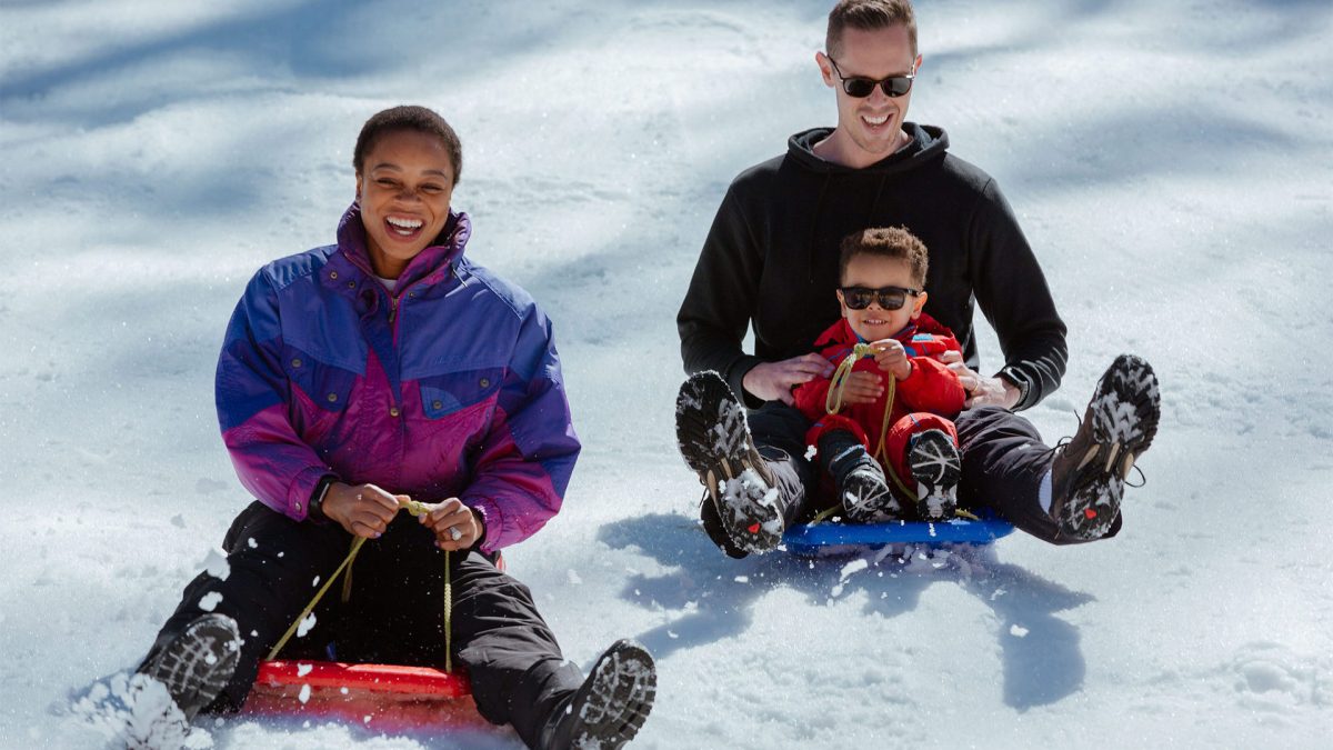 Family of three snow tobogganing