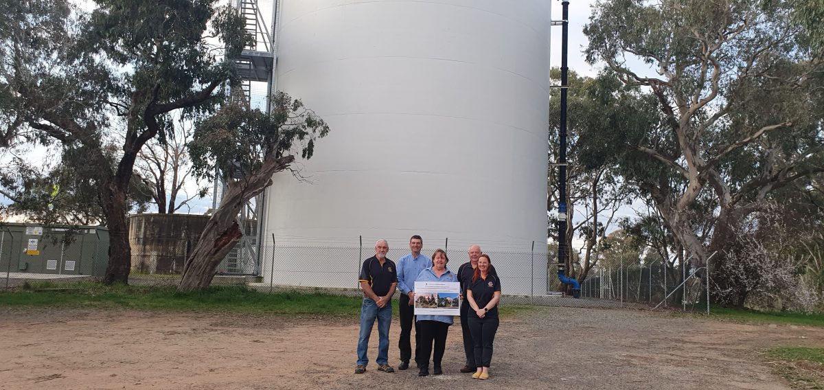 Four people in front of giant water tank