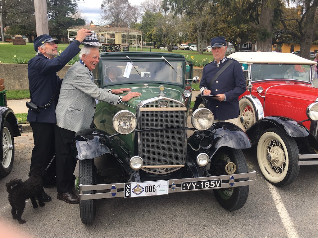 3 men standing around a Model A