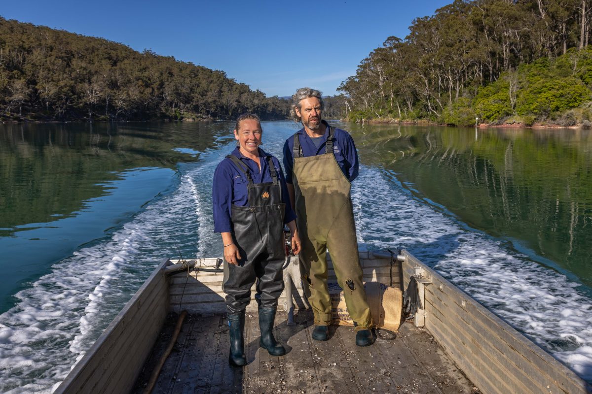 A man and woman in overalls and wellies standing on a boat