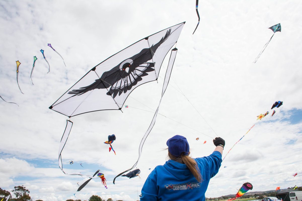 A woman flying a large black and white kite.