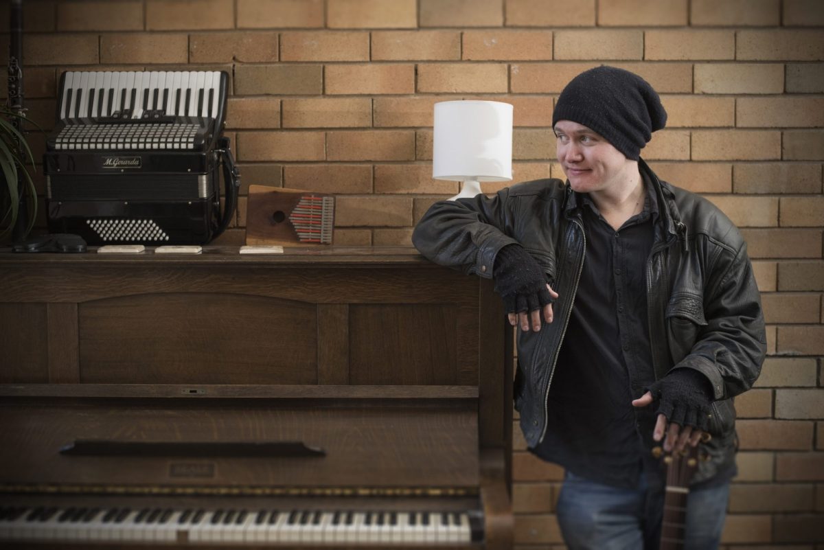 Man wearing hat leaning on piano