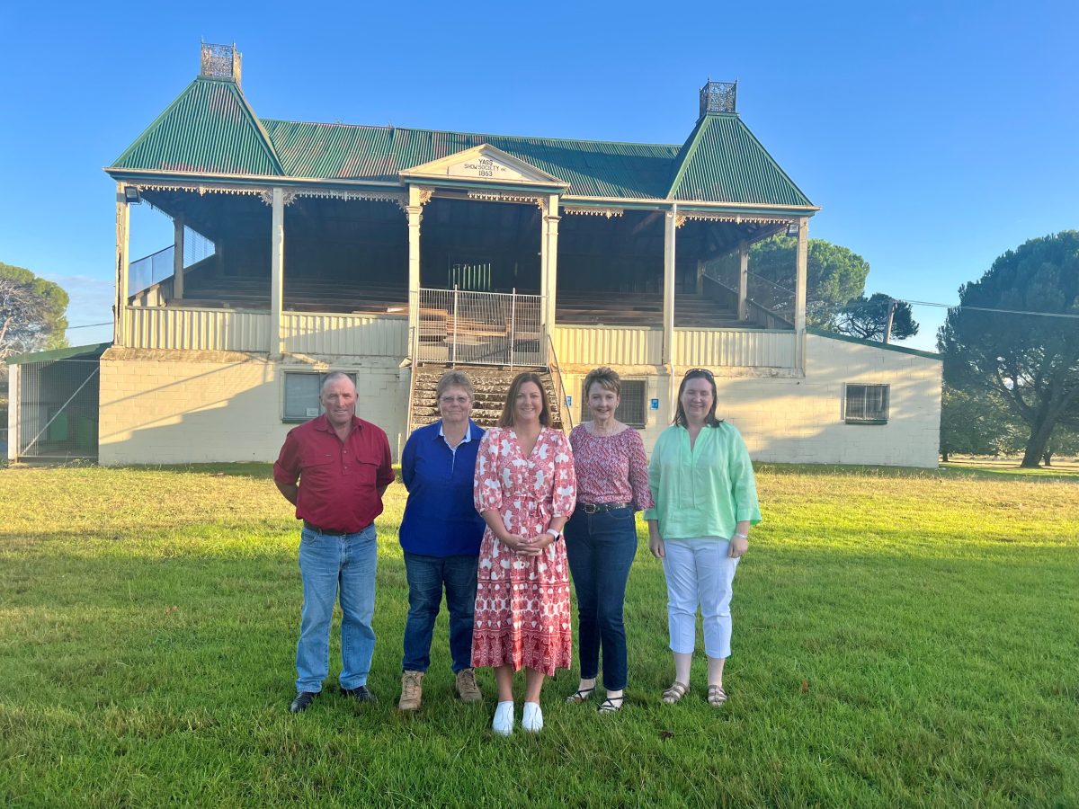 Man and four women in front of old grandstand