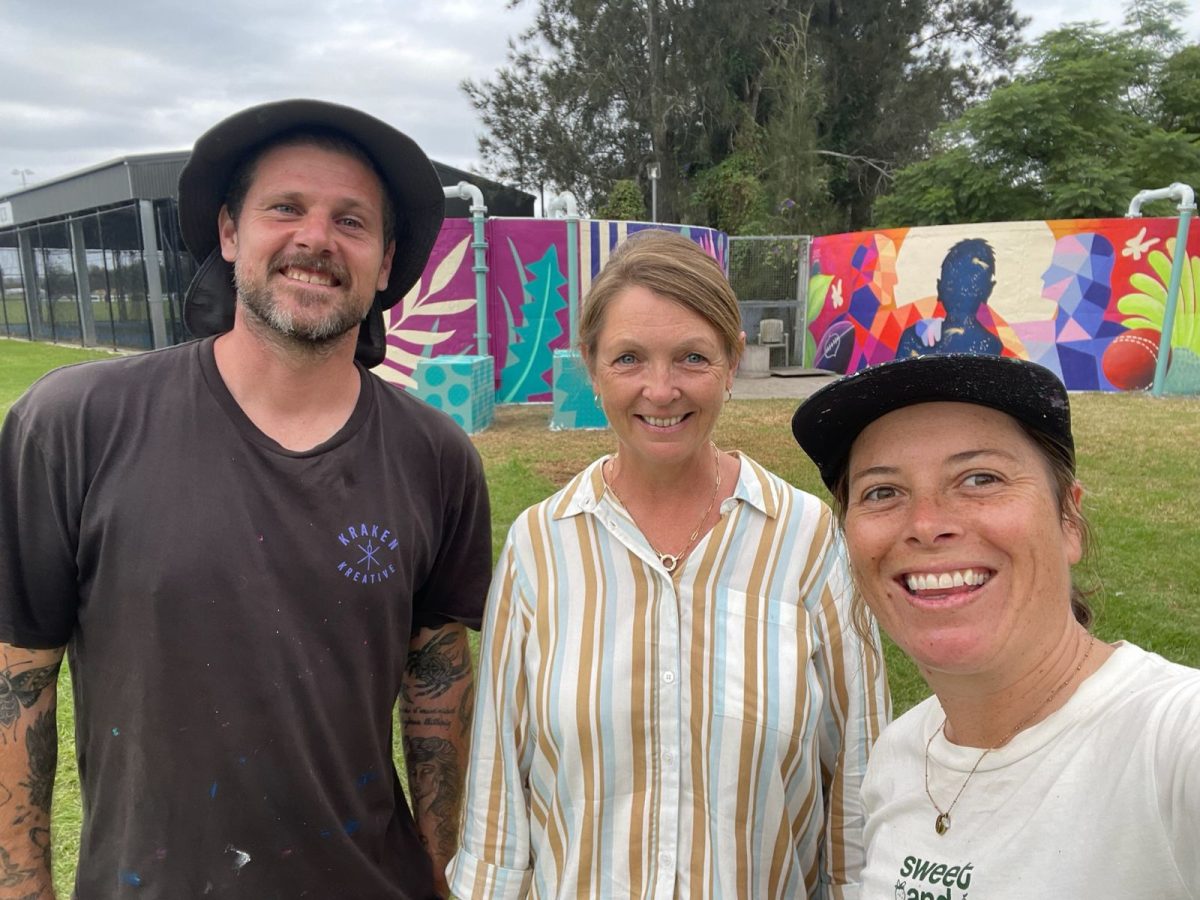 Three people in front of water tank mural