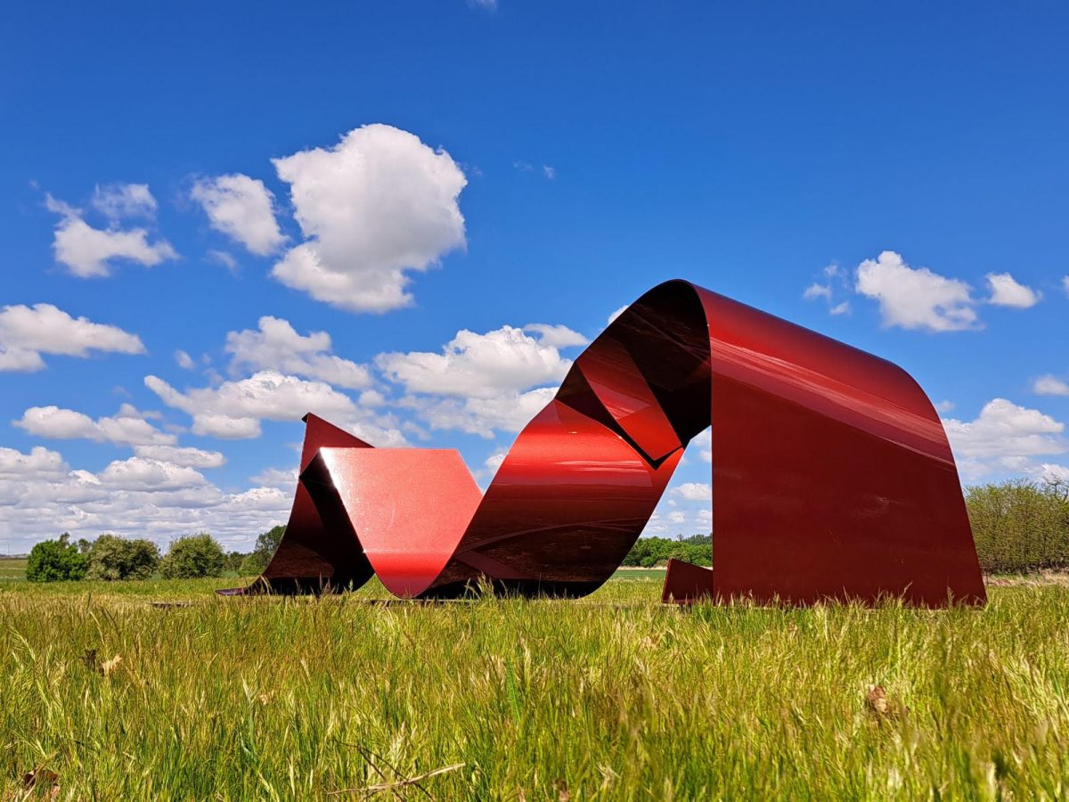 Large red steel sculpture in a field