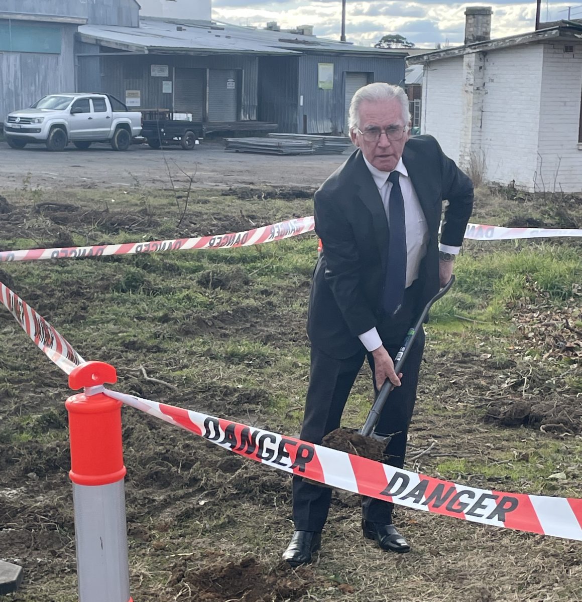 Man digging spade into area marked off with danger tape.