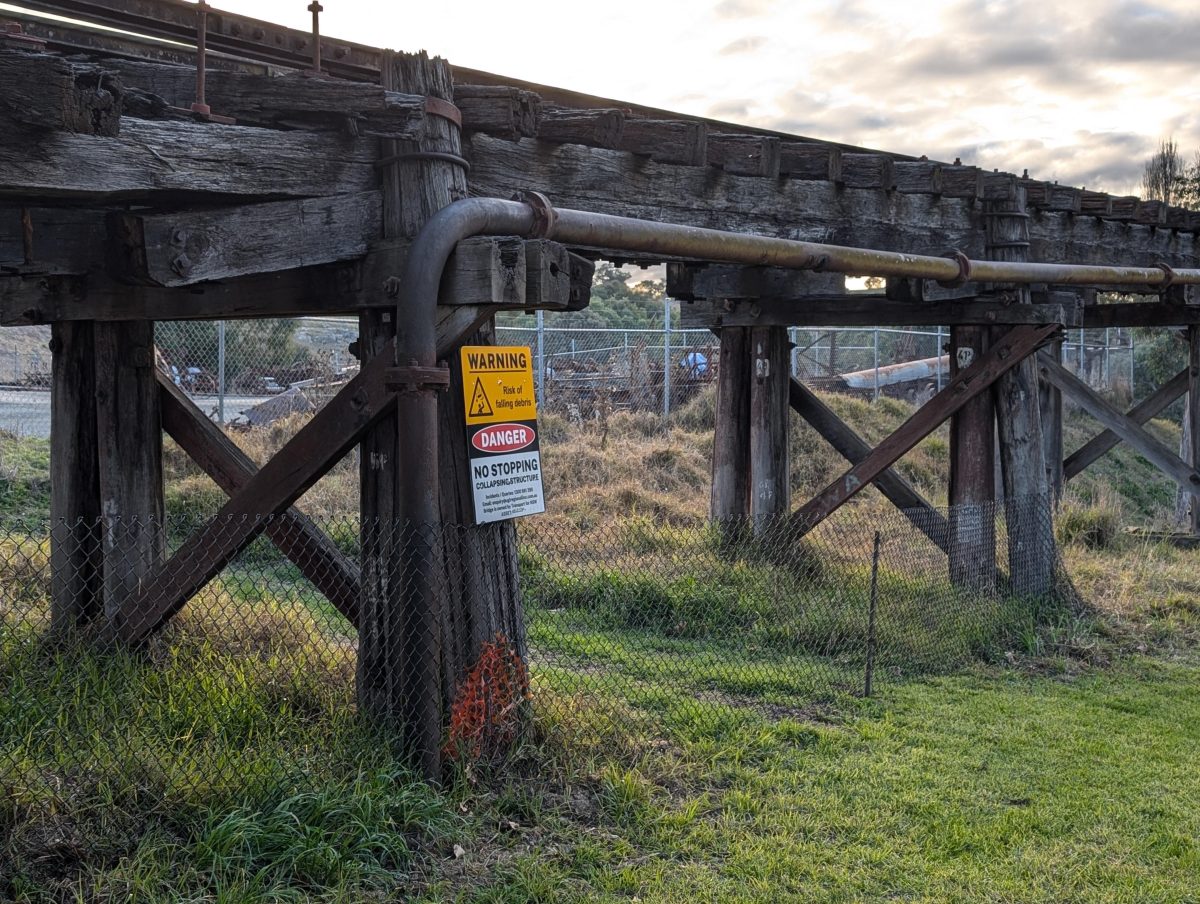 Old railway bridge with warning sign attached