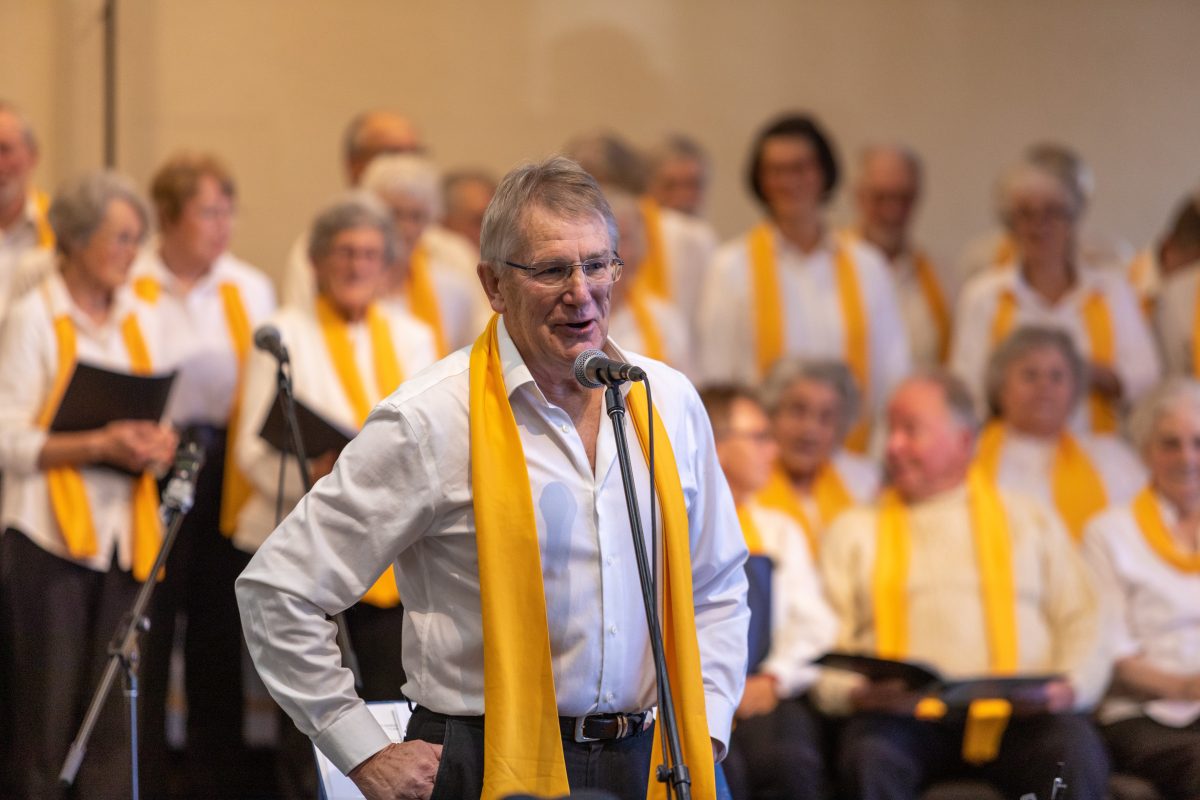 Man wearing yellow scarf in front of choir 