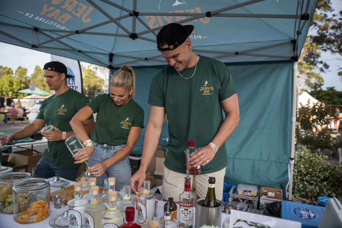 three people pouring drinks at a stall