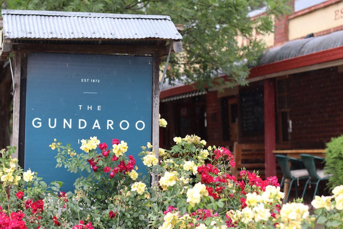 A sign partially obscured by flowers reads "The Gundaroo Inn"