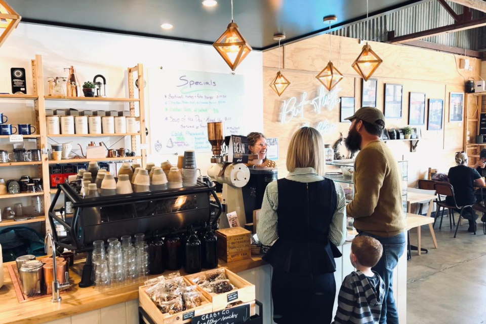 Two people and a child stand at counter at cafe.