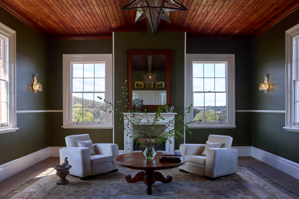 A green room with two arms chairs and timber ceiling.