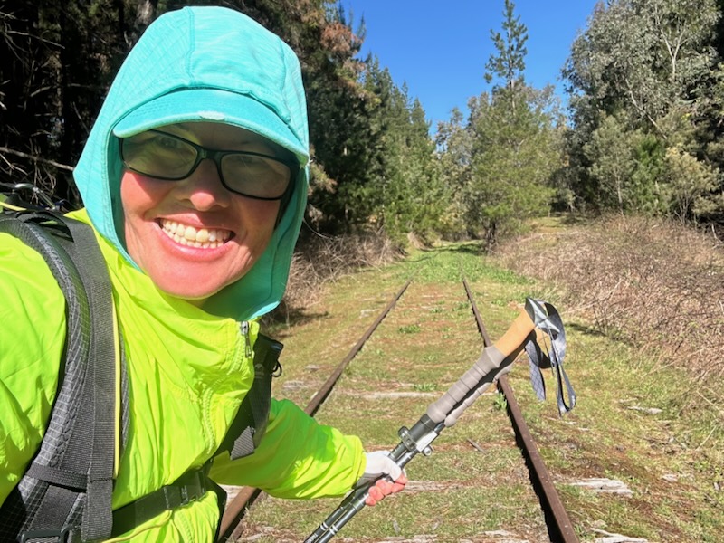 woman smiling in front of overgrown railway track